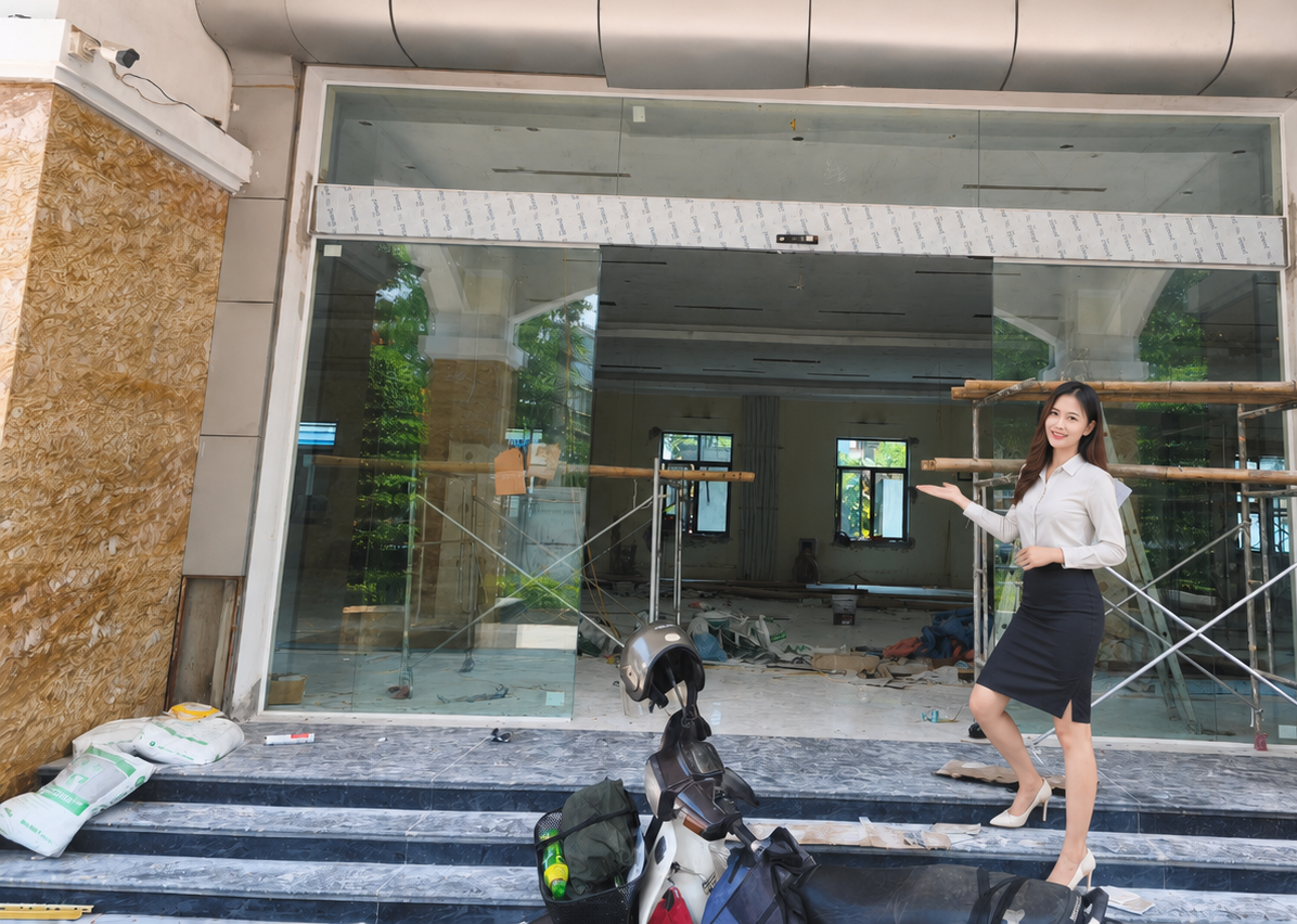 Cửa kính mặt tiền tòa nhà đang thi công với nhân viên văn phòng đứng giới thiệu phía trước